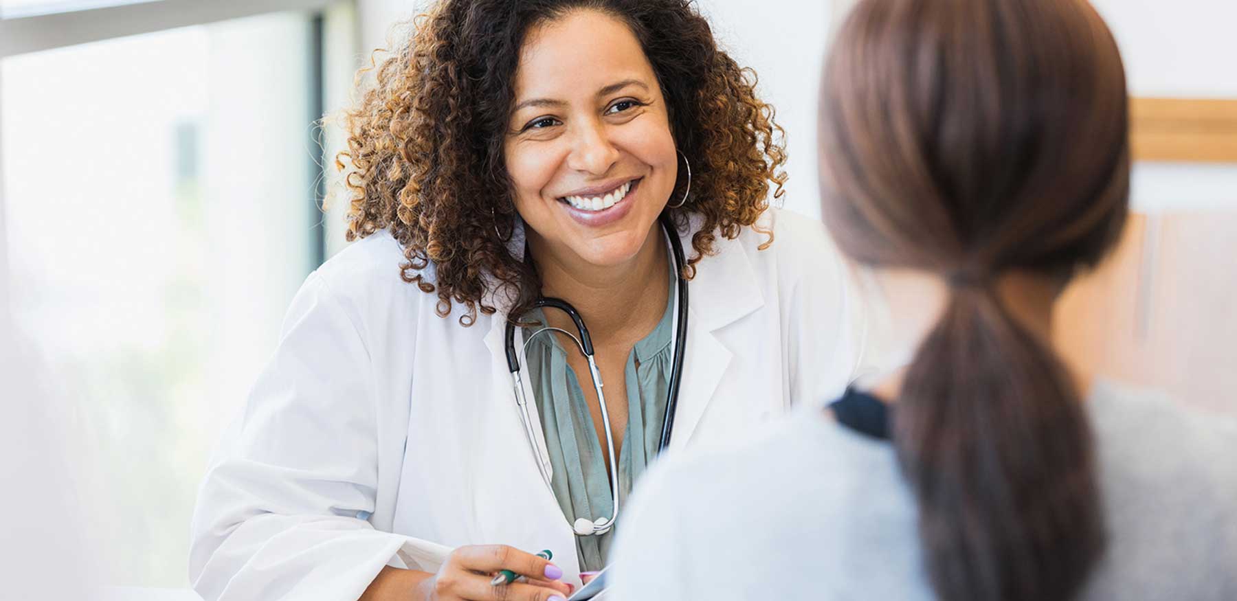 Smiling Black female doctor speaking with a patient